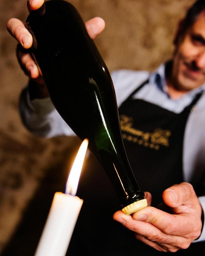 Cellar Master Xavier Berdin inspecting bottle of Champagne using a candle