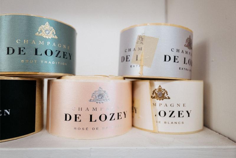 Collection of Champagne De Lozey labels on white shelf