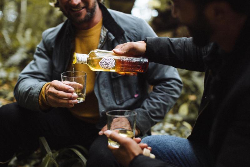 One man serving another a glass of The King's Ginger in the middle of the forest