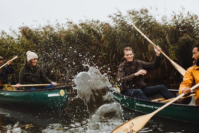 A group of friends in canoes splashing eachtother