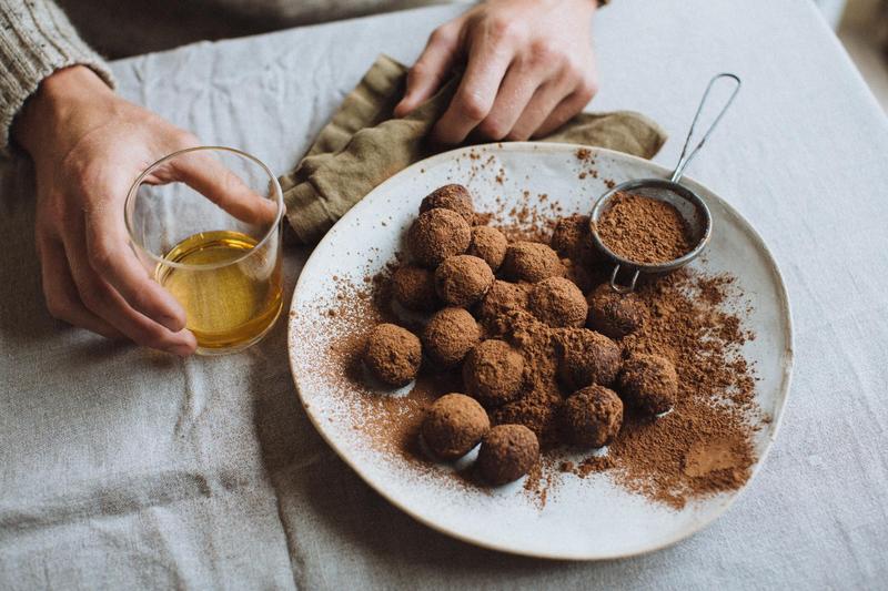 Top shot of hand holding a glass of The King's Ginger next to a plate of homemade chocolate truffles