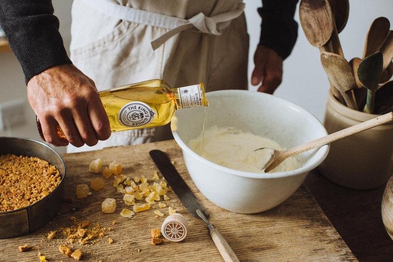 A person pouring The King's Ginger into a cake mixture in a countryside setting