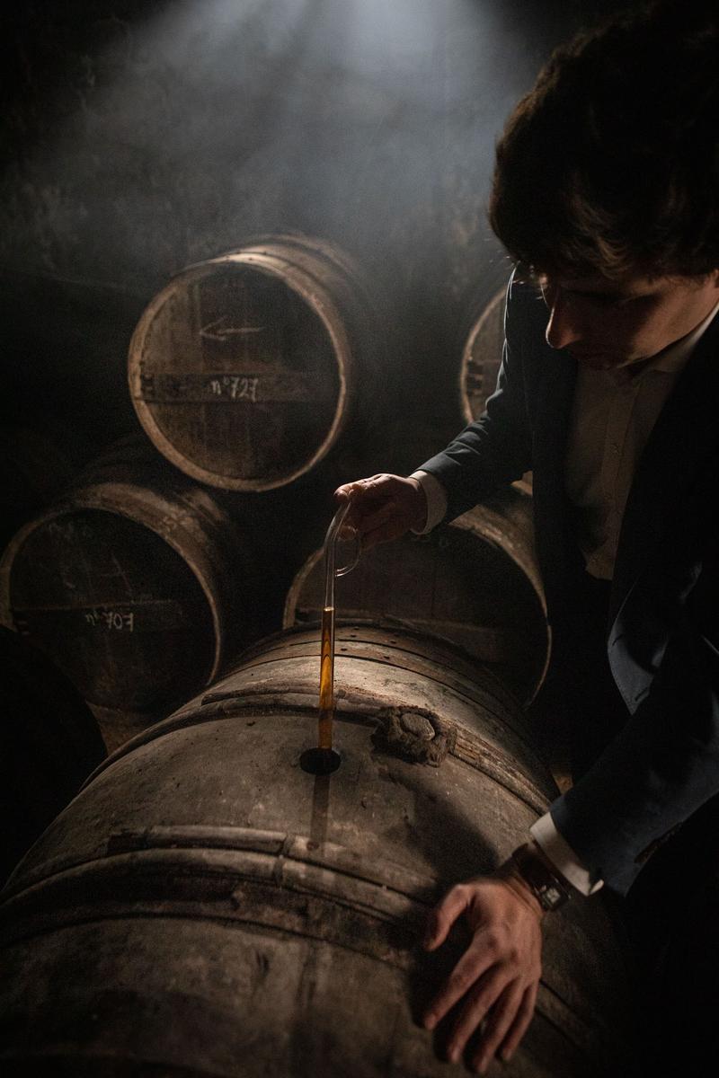 Noé Tesseron using pipette to extract a sample of Cognac Tesseron Experience from an old cask