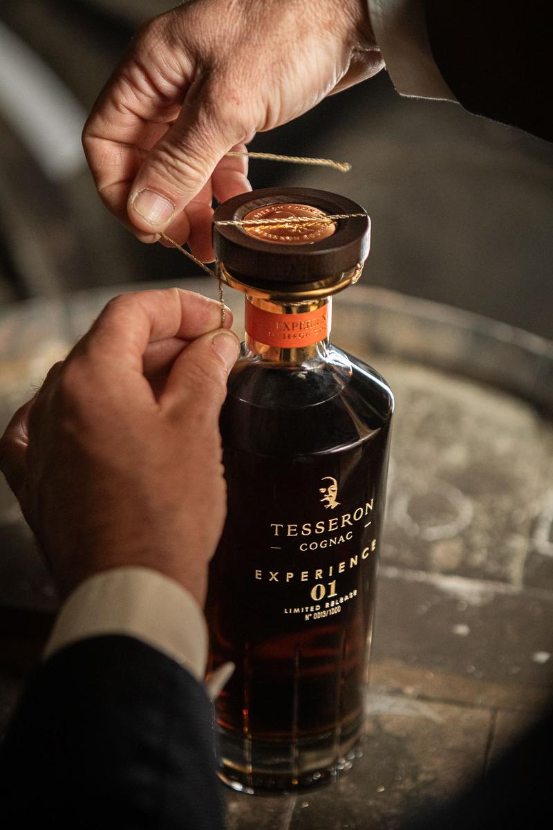 Bottle of Cognac Tesseron Experience 01 sitting between two glasses of Cognac