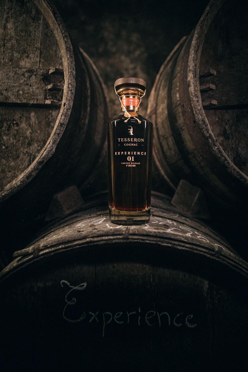 Bottle of Cognac Tesseron Experience 01 sitting between old barrels in the Tesseron crypt cellar