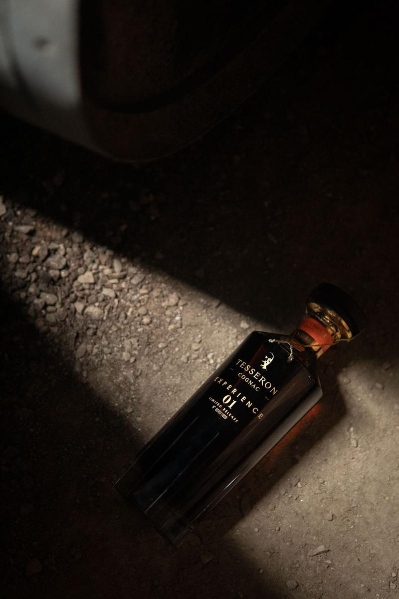 Bottle of Cognac Tesseron Experience illuminated by light shining between two old barrels